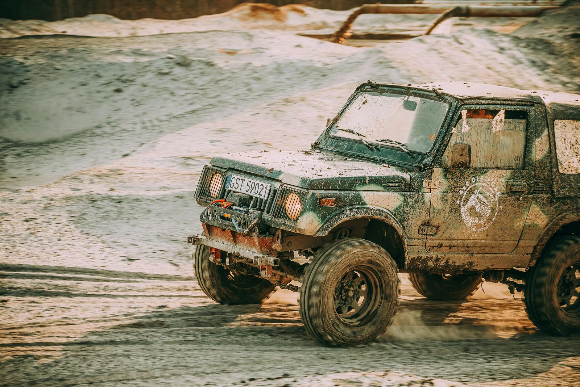 Jeep 4x4 jedzie po piaszczystym terenie, prezentując możliwości off-roadowe