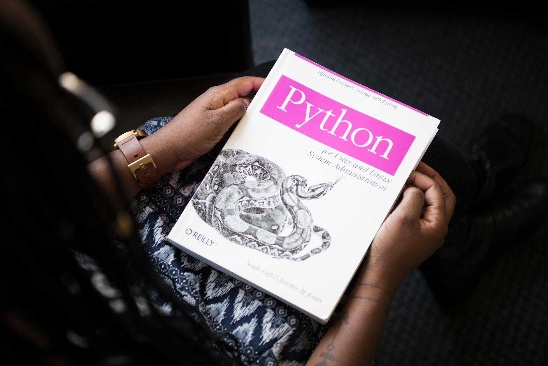 Osoba czyta książkę Python o administracji systemami Linux