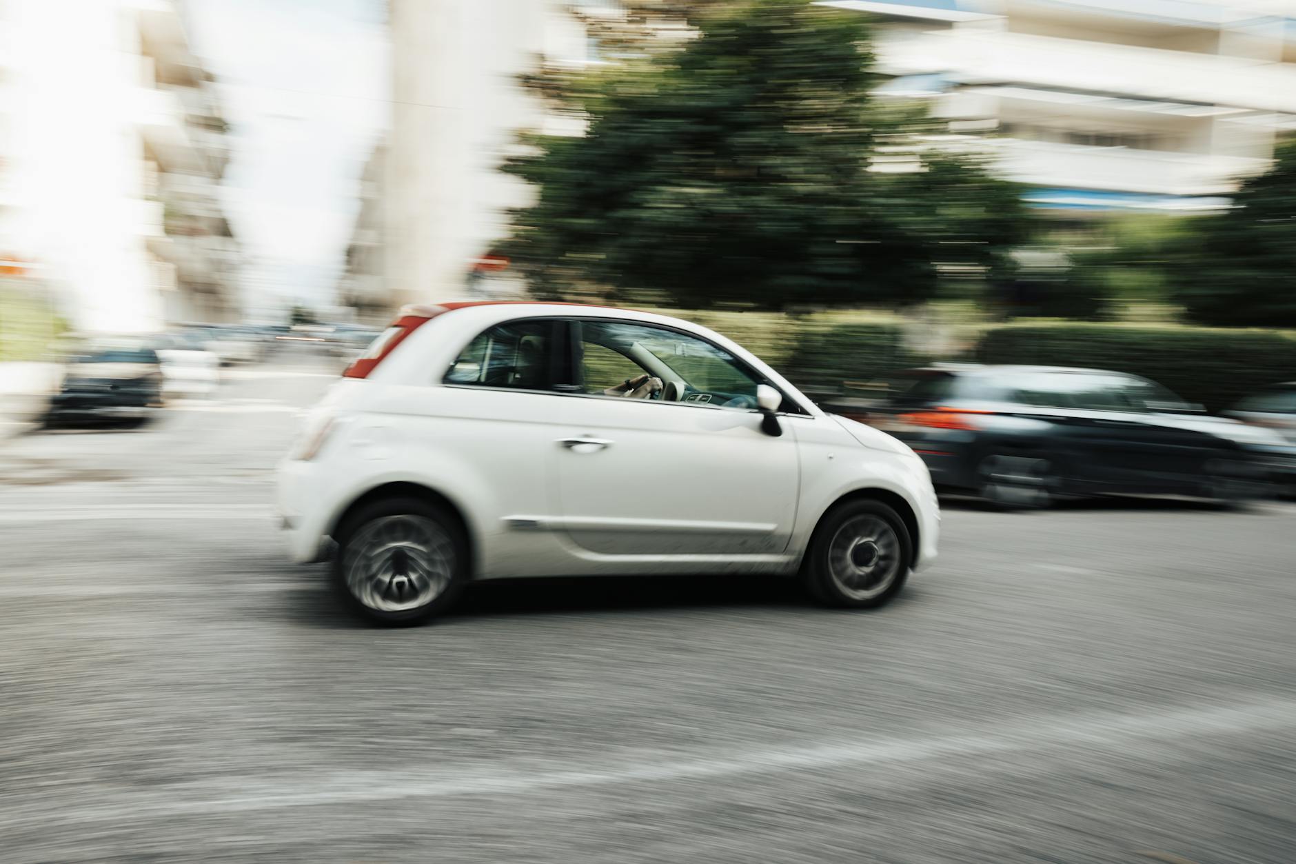 Białe Renault Clio jedzie szybko po miejskiej ulicy