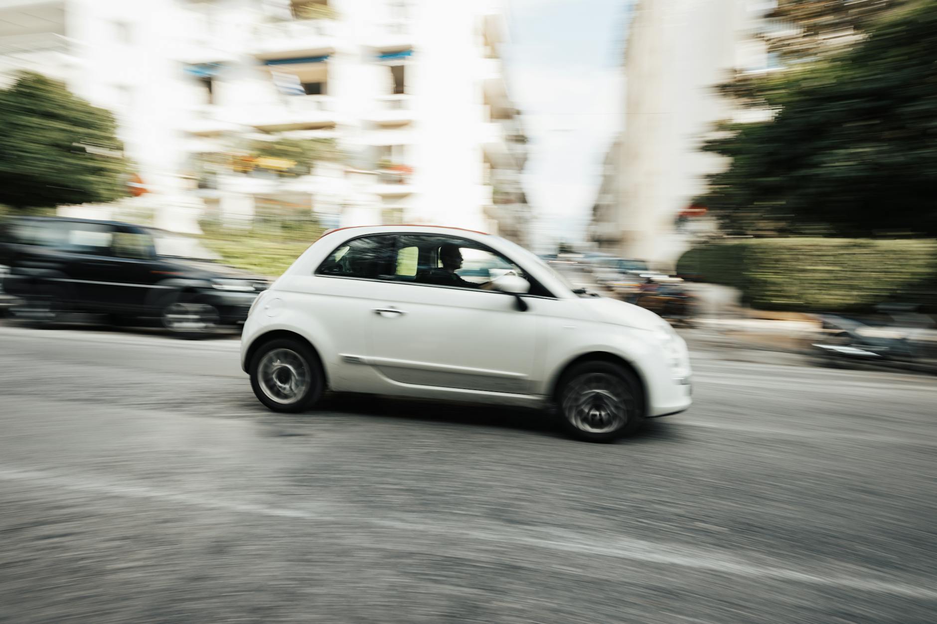 Białe Renault Clio jedzie szybko po ulicy w centrum miasta