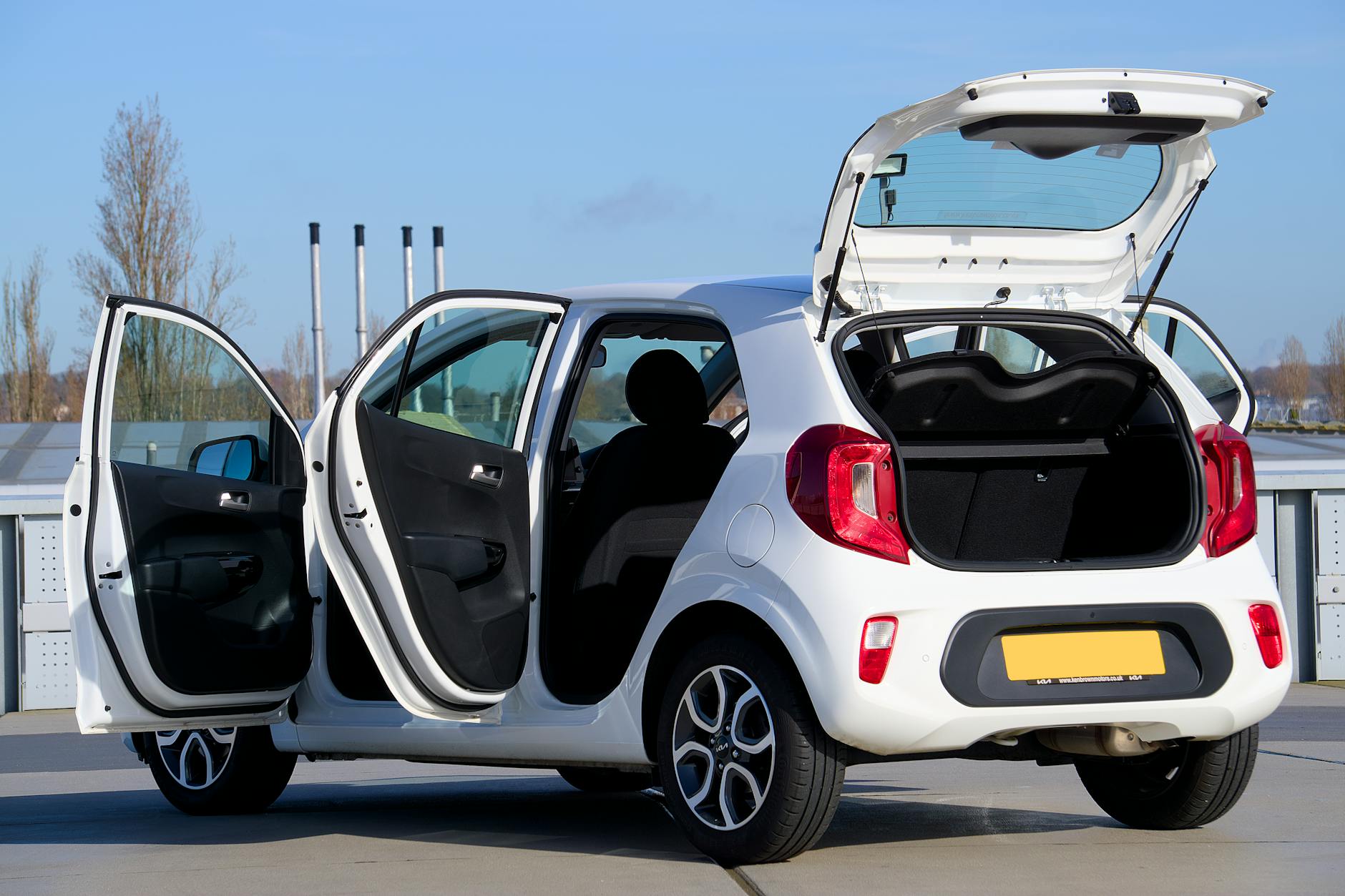 Biały kompaktowy Peugeot z otwartymi drzwiami i bagażnikiem w mieście