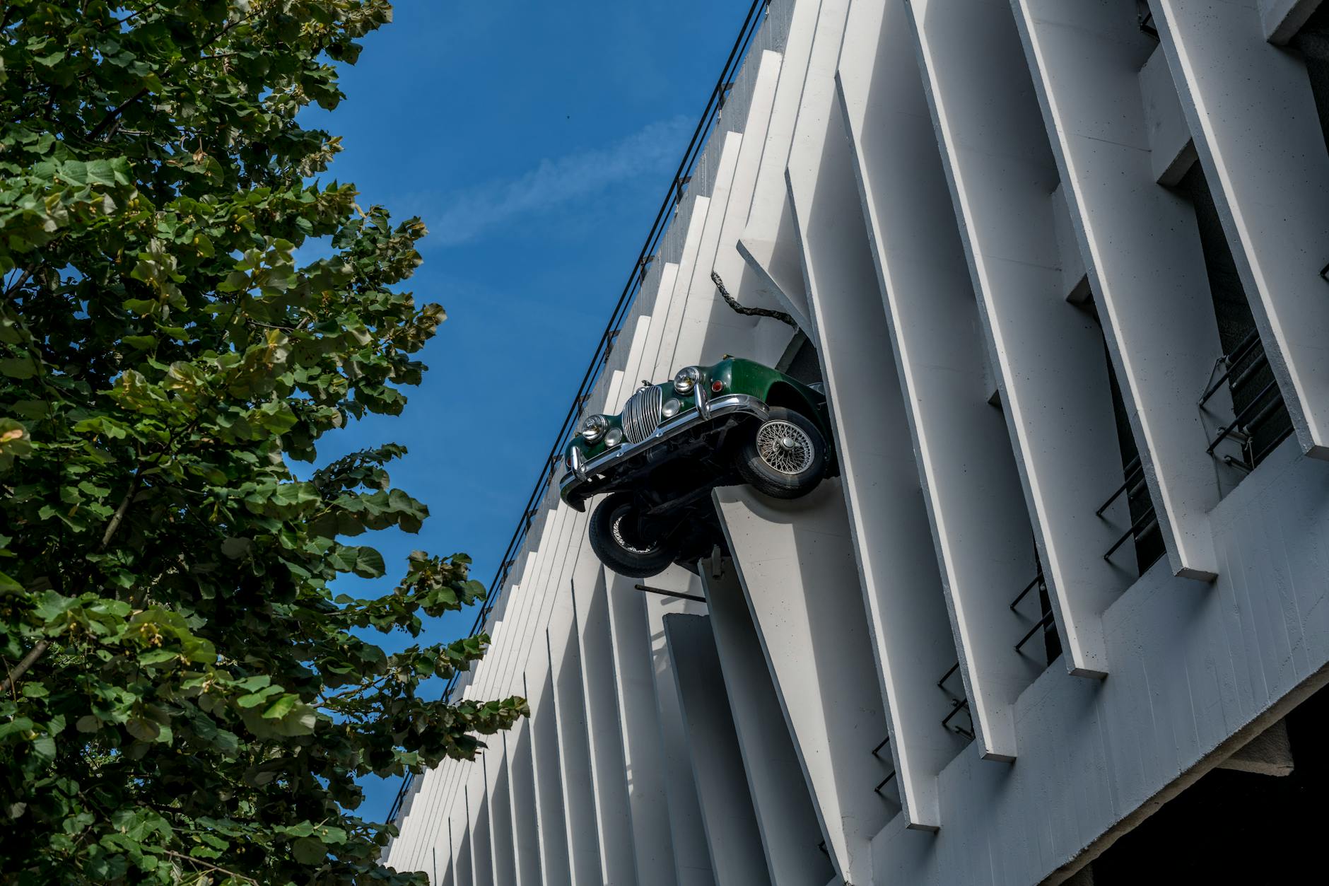 Rzeźba zabytkowego samochodu na nowoczesnej fasadzie budynku