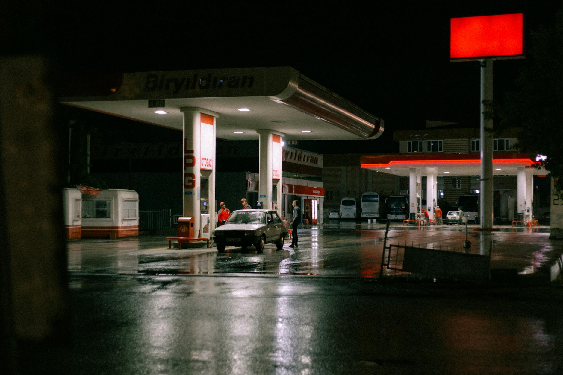 Samochód przy oświetlonej stacji paliw w nocy