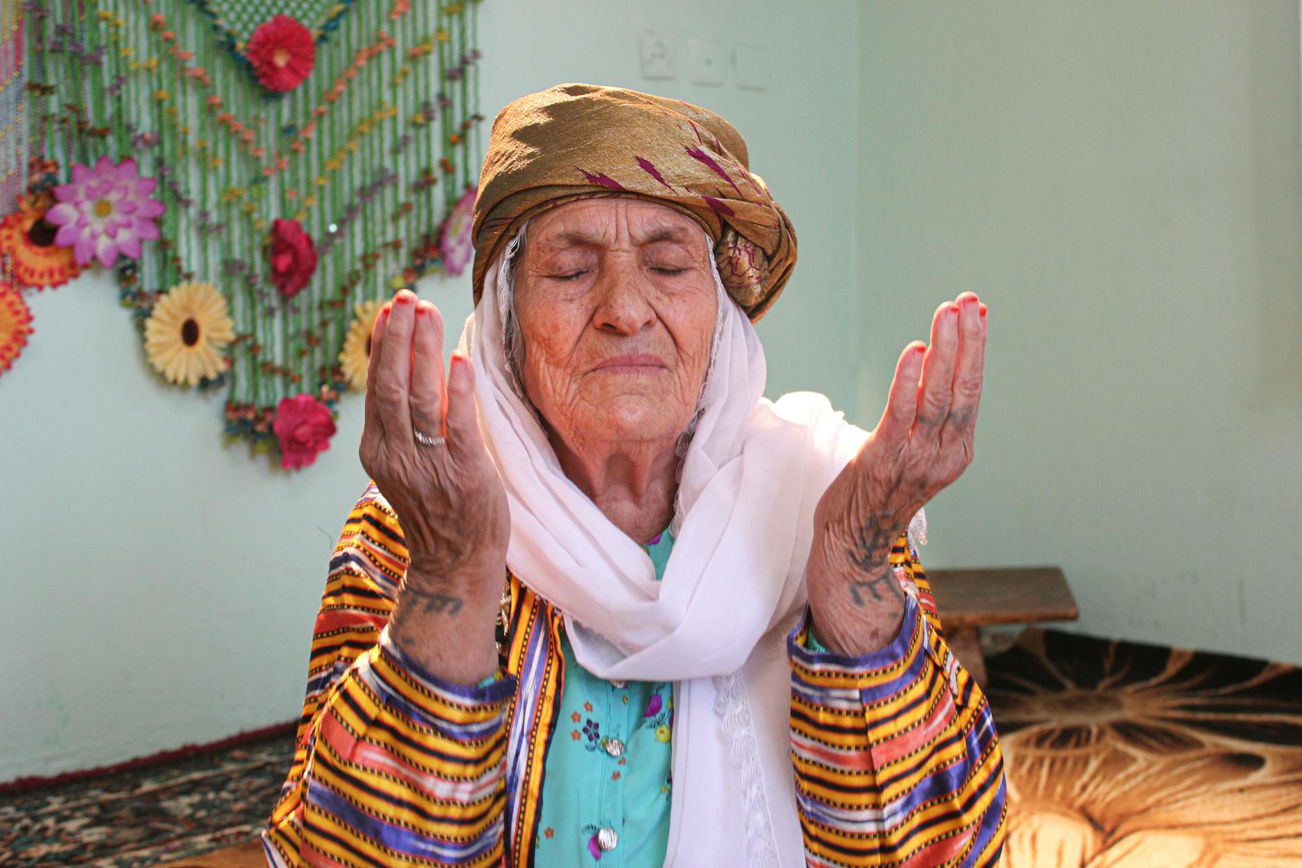 Starsza kobieta w tradycyjnym stroju modli się w ciszy w domu