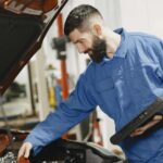 Mechanik w niebieskim kombinezonie ogląda silnik Kii w warsztacie