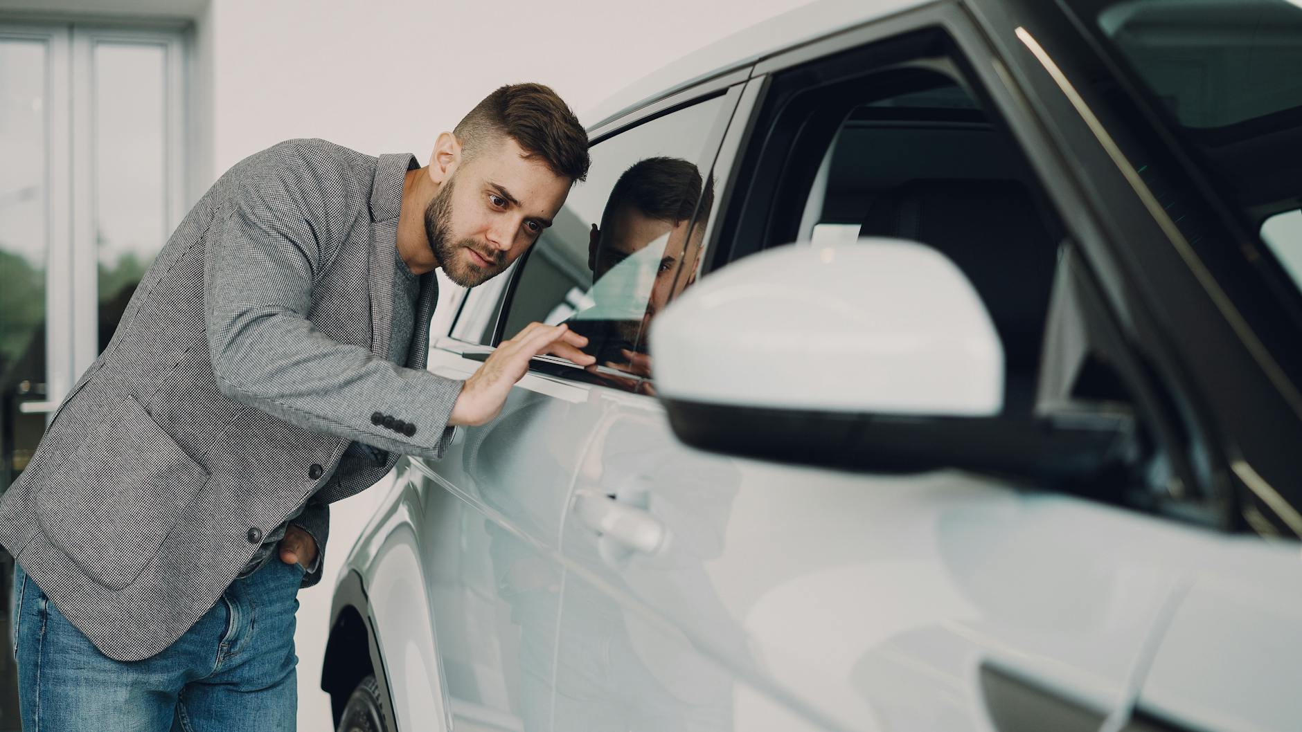 Mężczyzna ogląda białe BMW w salonie przed zakupem