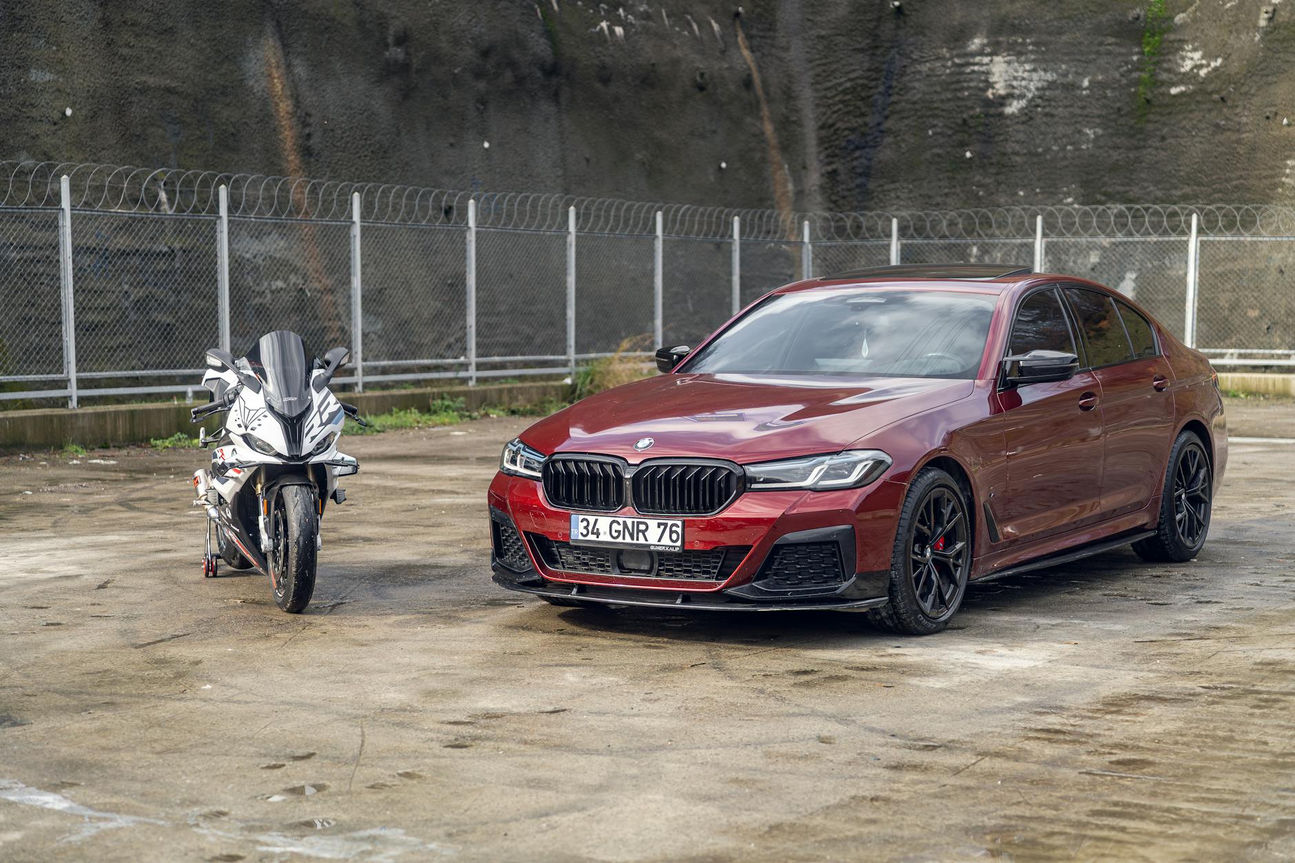 Czerwony samochód sportowy i motocykl zaparkowane na betonowym placu