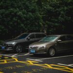 Dwa zaparkowane auta, SUV i sedan, na zacienionym miejskim parkingu