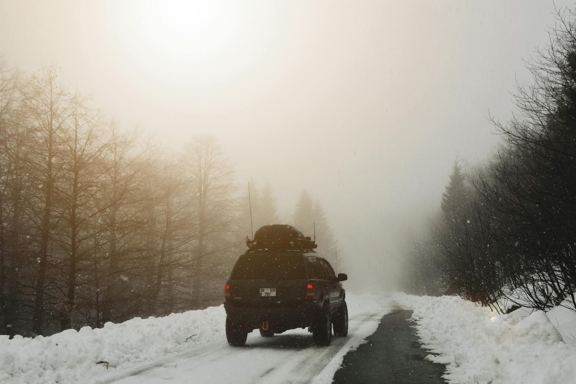 Jeep typu SUV jedzie zimą po ośnieżonej drodze w lesie