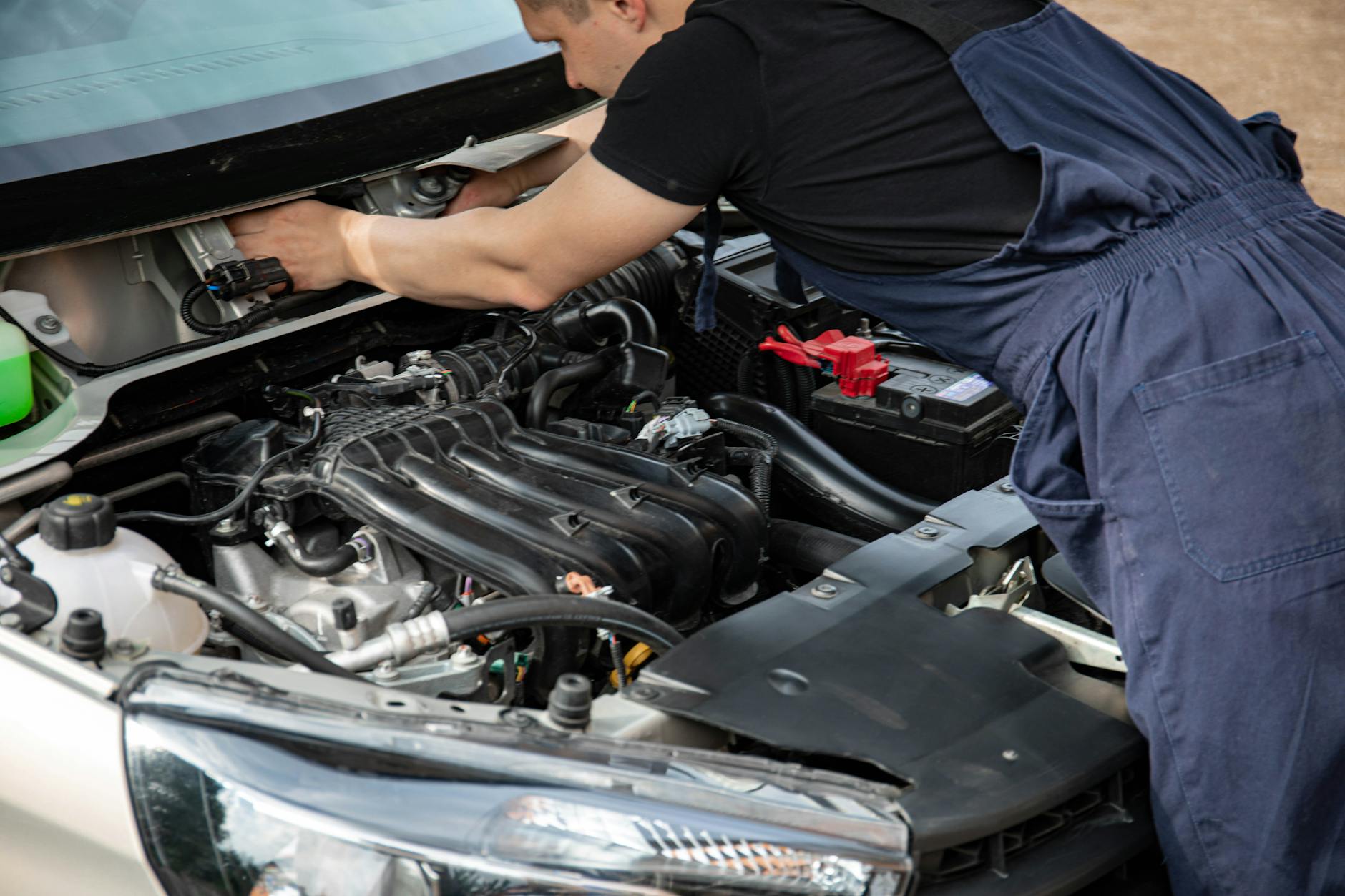 Mechanik w niebieskim kombinezonie sprawdza silnik Renault pod maską