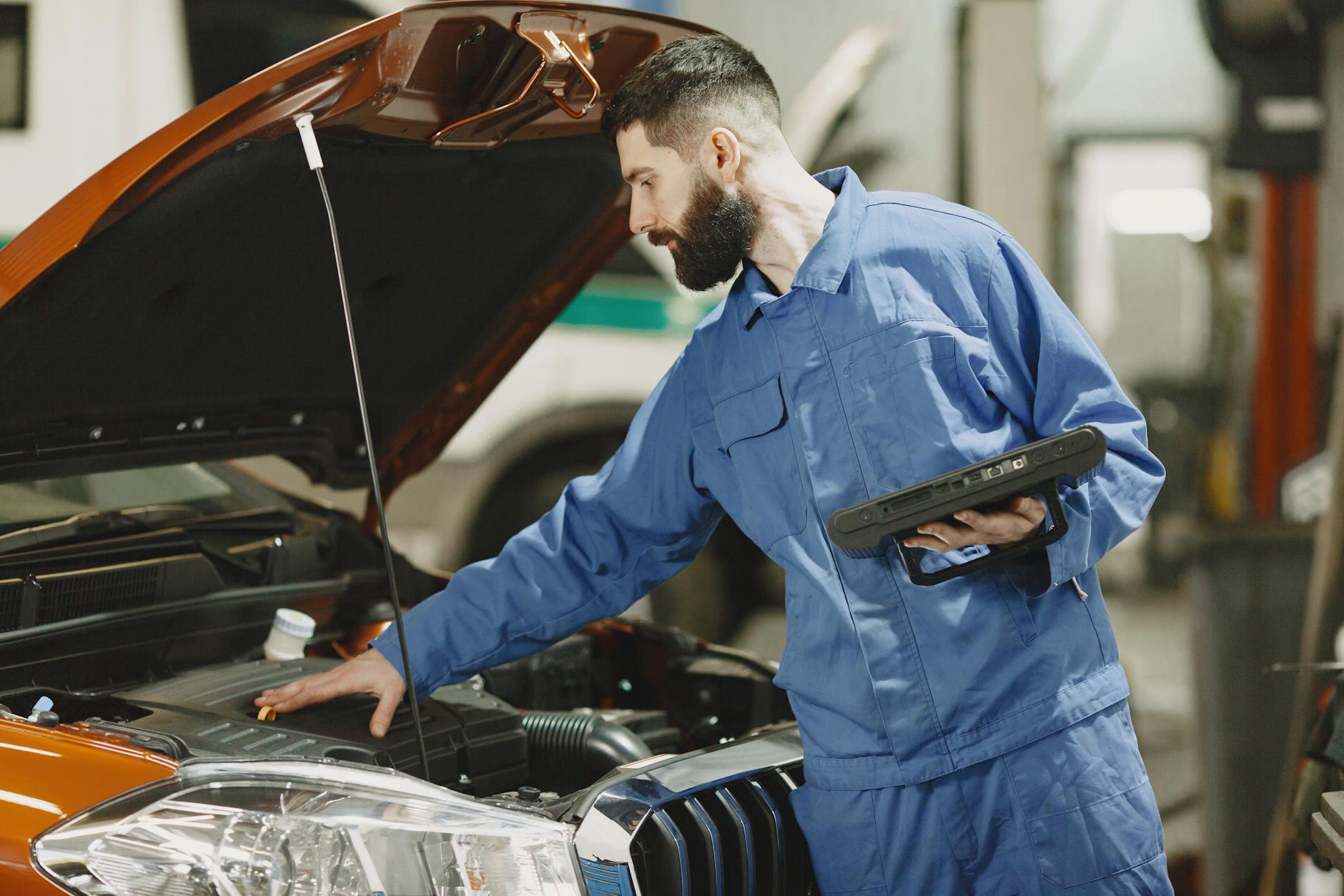 Mechanik w warsztacie sprawdza silnik Renault pod otwartą maską