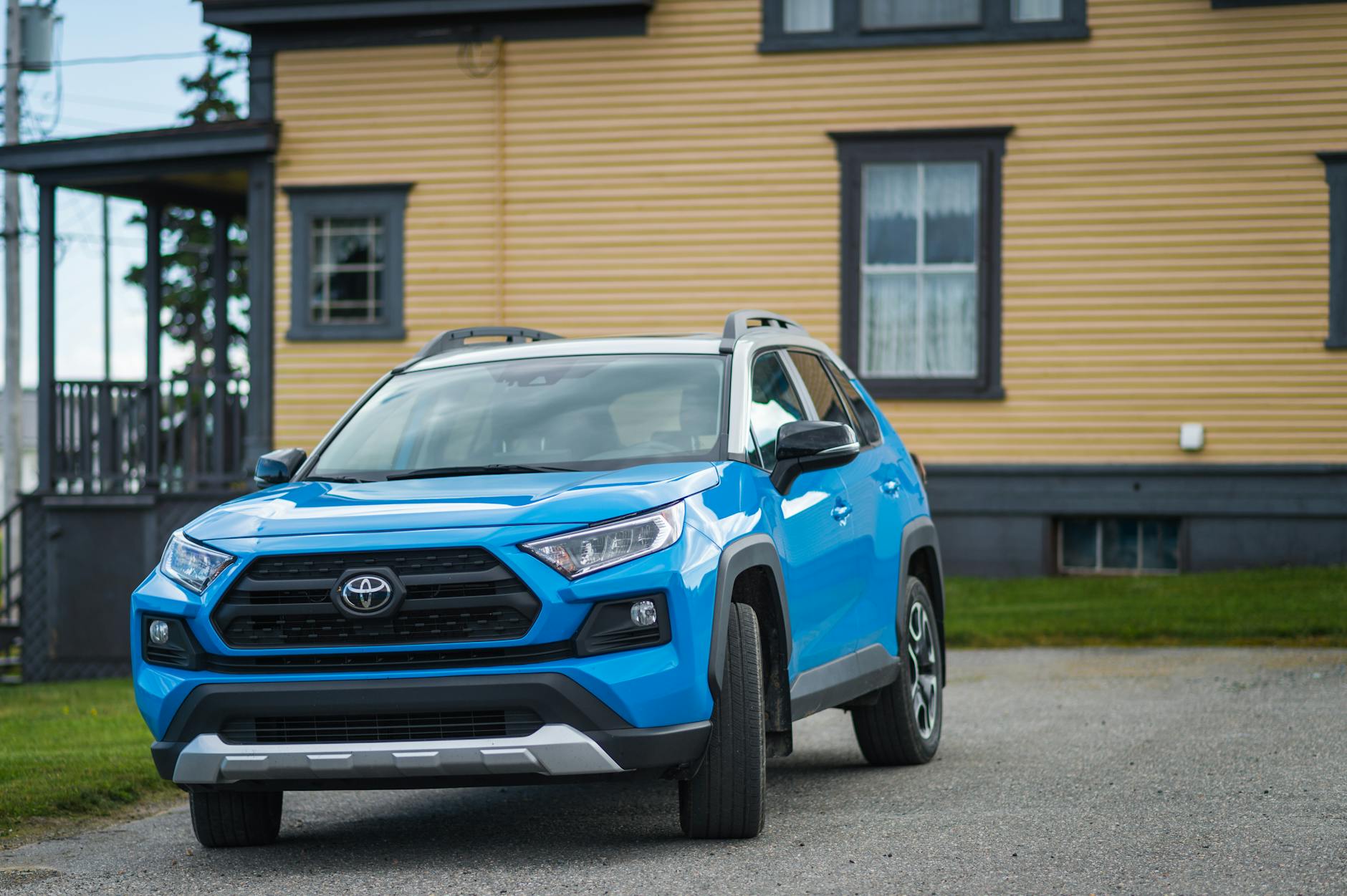 Niebieska Toyota RAV4 zaparkowana przed domem