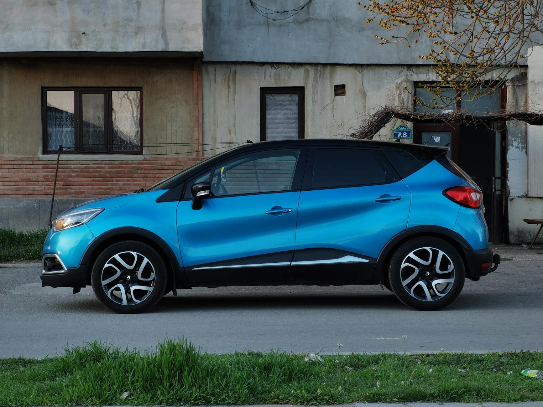 Niebieski miejski SUV Toyoty zaparkowany przy zabytkowej kamienicy