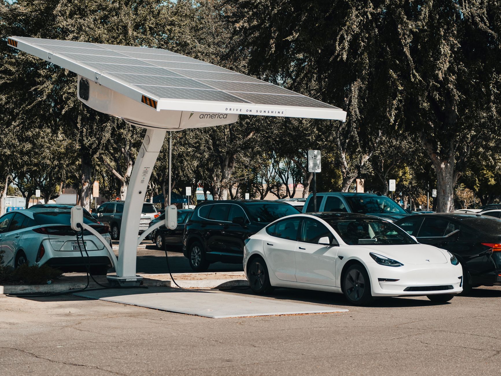 Elektryczny samochód Tesla ładowany przy zewnętrznej stacji z panelami słoneczny