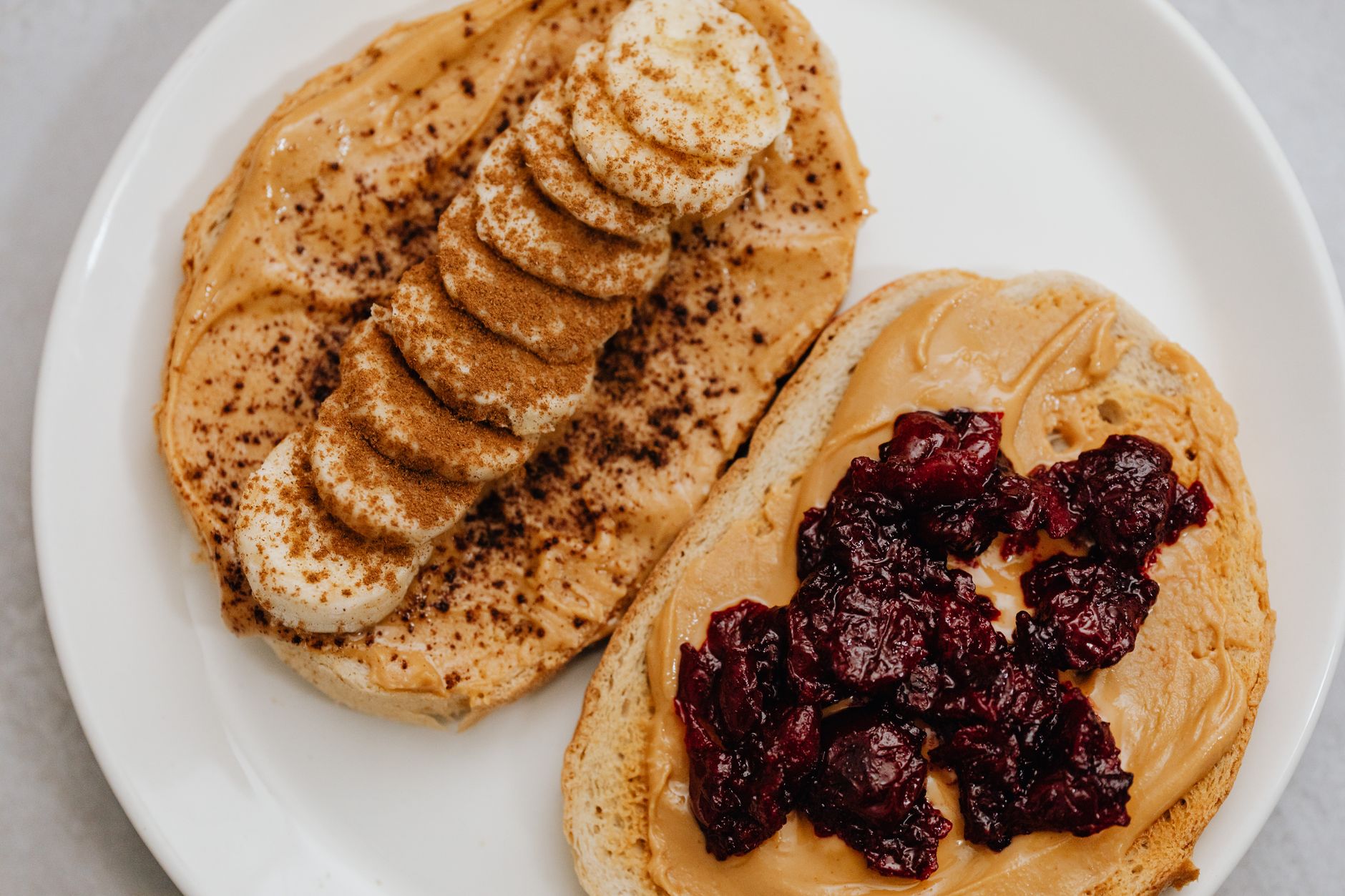 Tost z masłem orzechowym, bananem i dżemem na białym talerzu